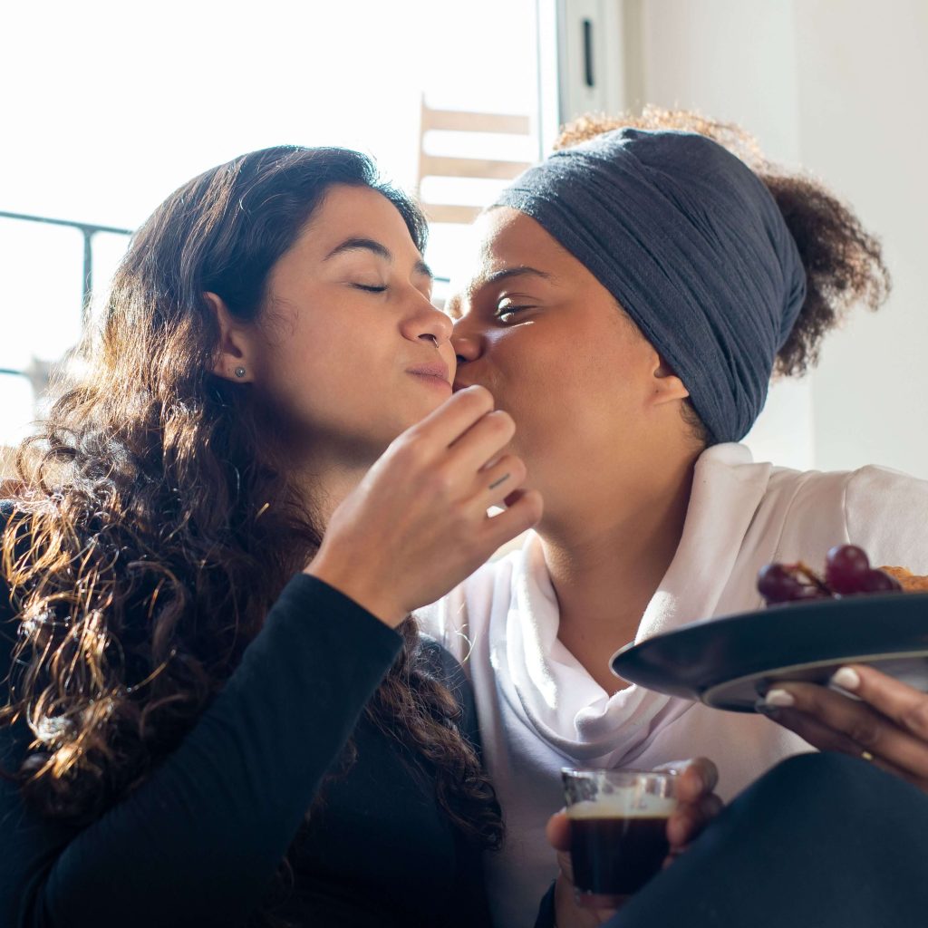 LGBTQ+ couple | lgbtq therapy alabaster | lgbtqia+ therapist alabaster | lgbtq therapist pelham | chronic pain | alabaster, al | pelham, al | gardendale, al A biracial LGBTQ+ couple showing each other affection while sharing a snack. An affirming LGBTQIA+ therapist can help you navigate neurodiversity & trauma.. IHS is here to help!
