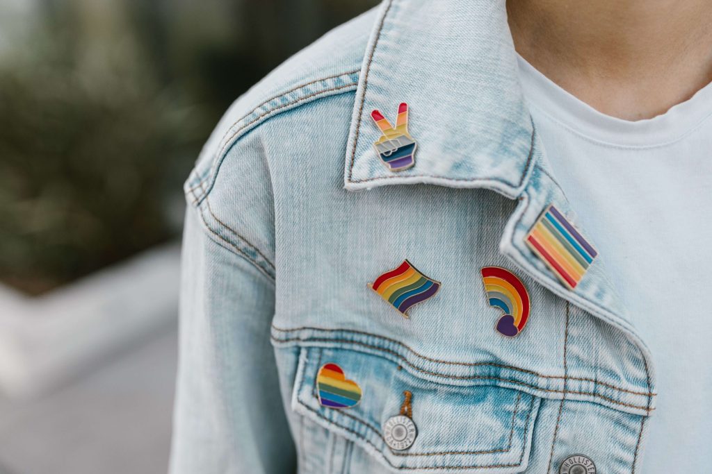Different Pride pins attached to a light denim jacket. Finding an LGBTQIA+ affirming therapy in Alabama should be accessible. Reach out to IHS today to get paired with a therapist.