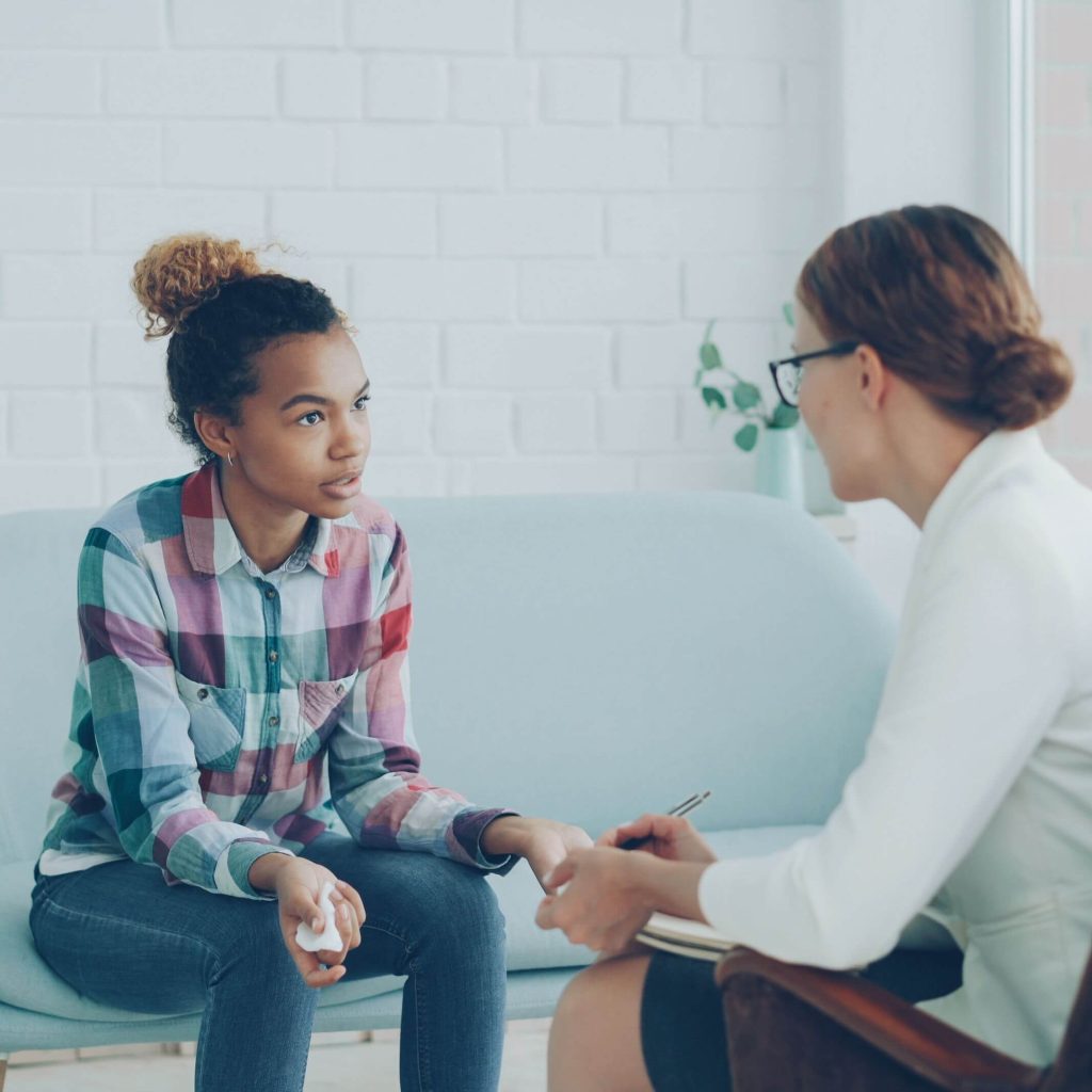 teen talking to therapist | lgbtq affirming therapist gardendale, al | lgbtq therapy gardendale, al | lgbtq+ affirming therapy gardendale, al | gardendale, al | alabaster, al | pelham, al A biracial teenager talking to a therapist in a bright lit room. Representing how IHS offers LGBTQIA+ affirming therapy in Gardendale, AL. Learn more here!