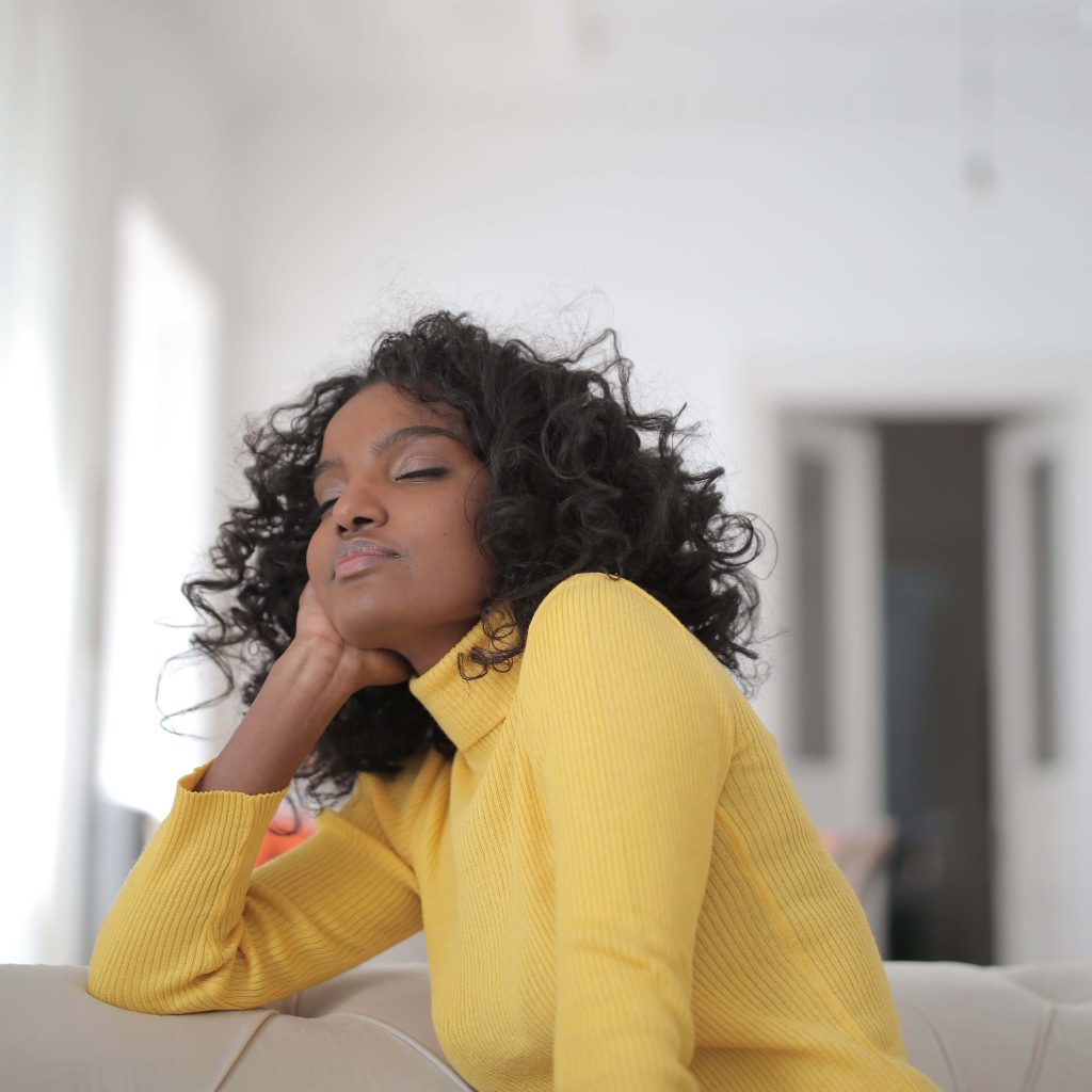 A woman wearing a bright yellow turtle neck sweater closing her eyes in relief. Representing how psychiatry in Alabama can support your healing journey. Contact IHS today.