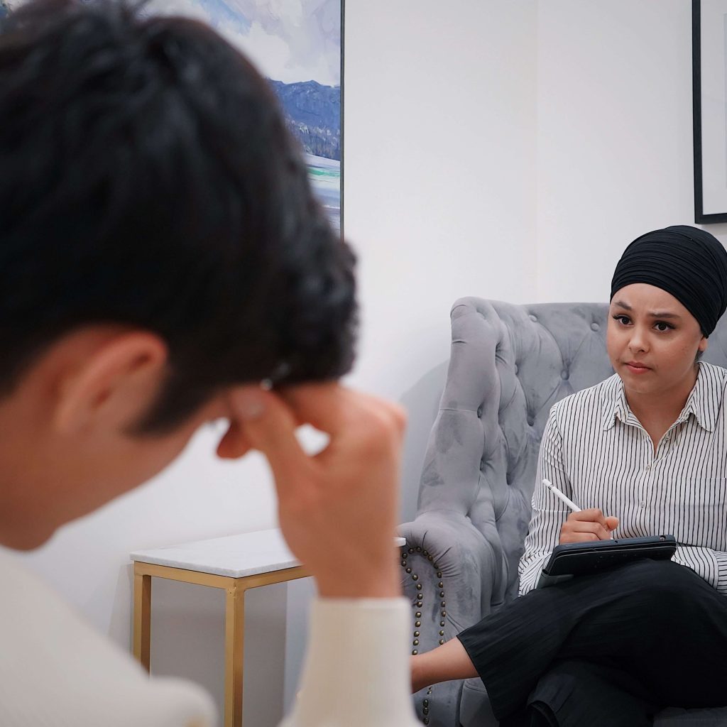 A professional therapist taking notes on an Ipad while talking to a client. IHS offers neurodivergent affirming therapy and chronic illness therapy throughout Alabama. Learn more here!